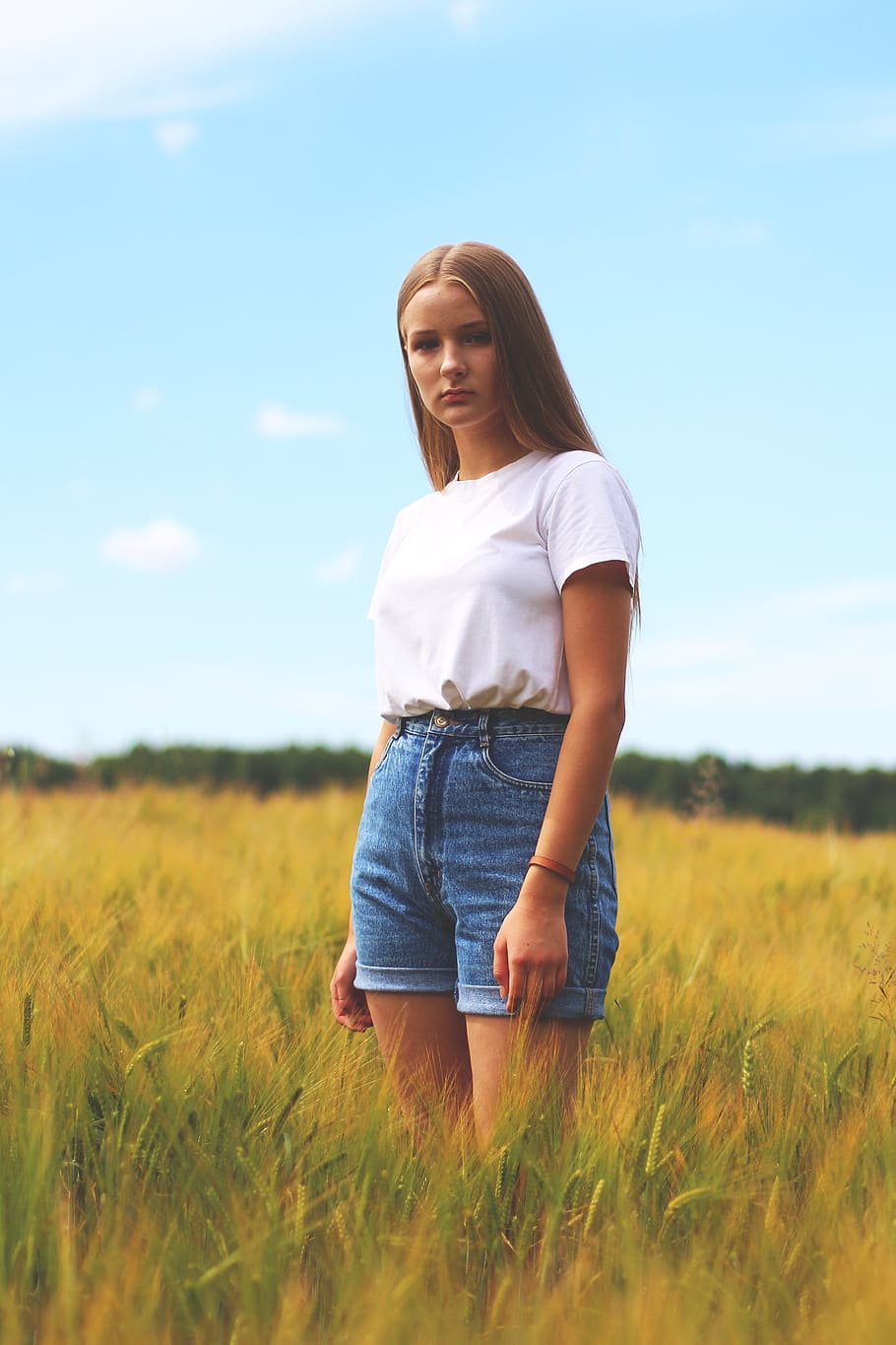 Woman Wearing White Crew-neck T-shirt, Blue Denim Cuff Short Shorts While Standing on Grass Field HD wallpaper