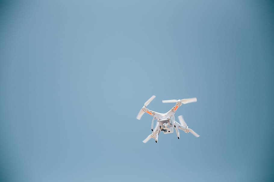 A drone in flight with clear sky in the background, clouds, control