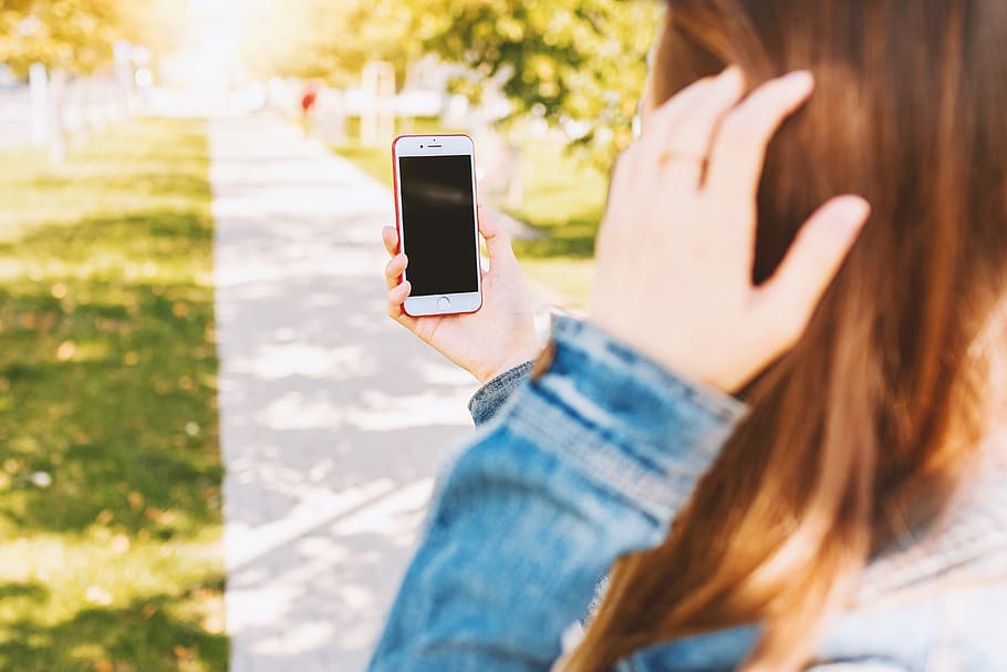 Mockup image of a woman using smartphone with blank black screen at outdoor HD wallpaper