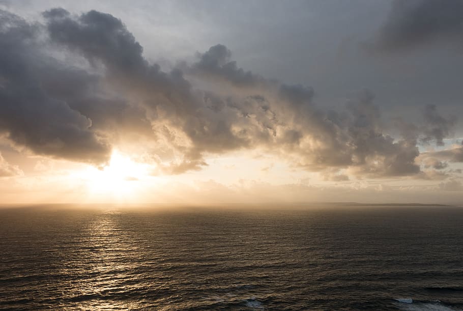 sunset, clouds, water, waves, cliffs, shore, explosion, rays HD wallpaper