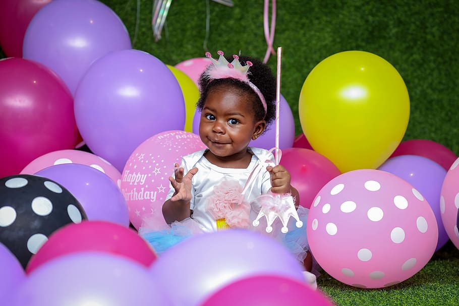Toddler Girl Sitting On Ground Surrounded By Balloons, birthday