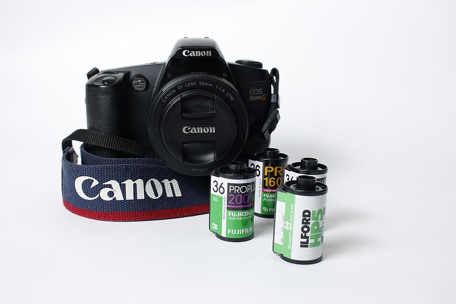 Black Canon Eos Camera Beside Four Camera Films On White Surface HD wallpaper