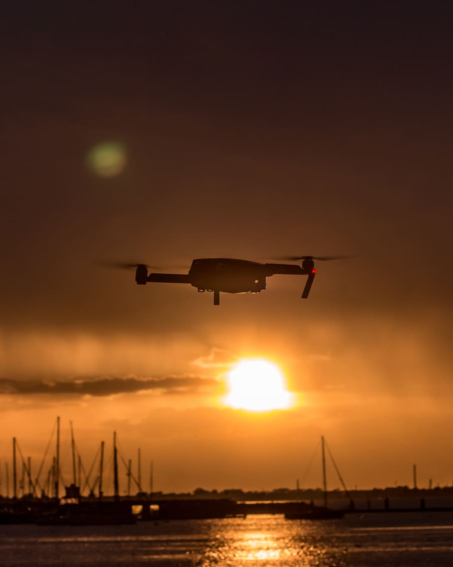 White Quad-copter Drone Flying over Body of Water during Golden Hour HD wallpaper