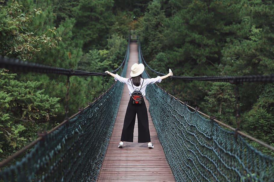 woman standing on hanging bridge surrounded by trees, person HD wallpaper