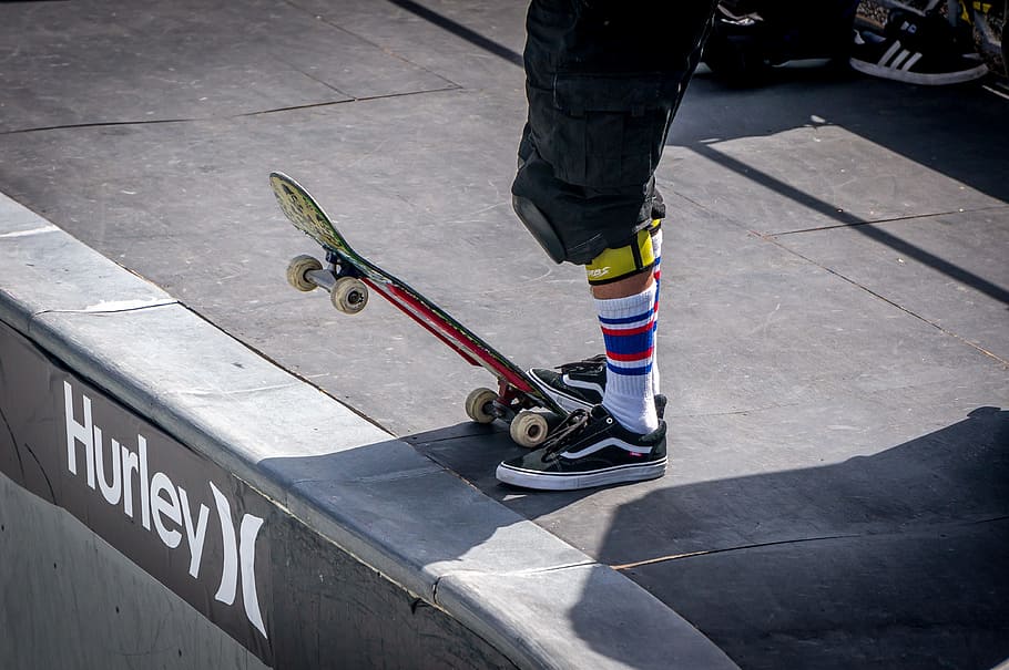 person stepping skateboard on tip beside Hurley signage, skateboarding, HD wallpaper