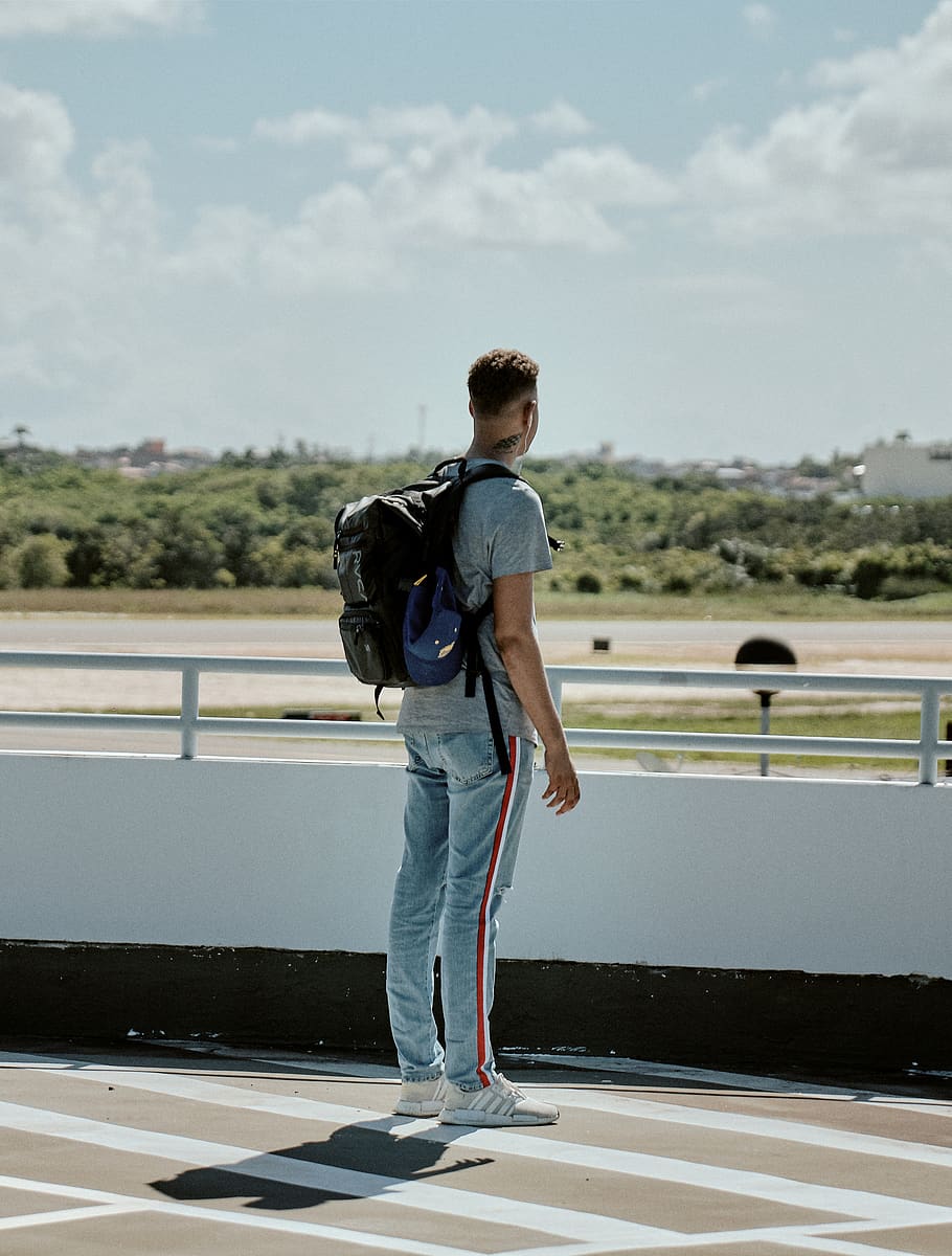 man with black backpack stands facing road, person, human, pants HD wallpaper