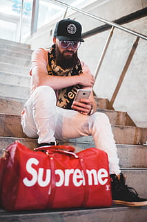 HD wallpaper: man sitting on stairs with red Louis Vuitton X Supreme  leather duffel bag
