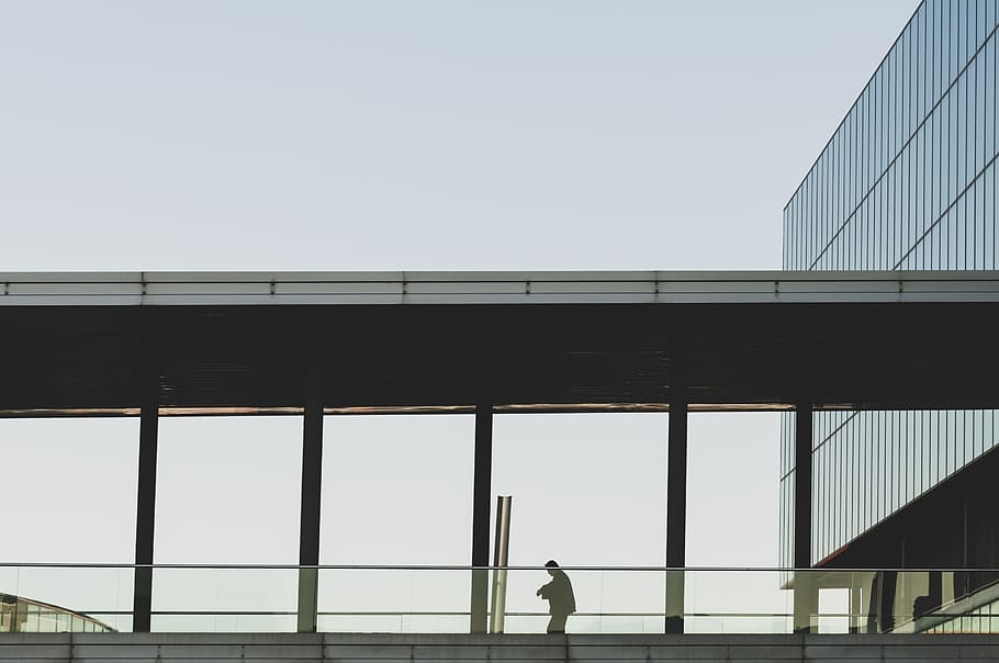 person walking on bridge with roof near building during daytime HD wallpaper