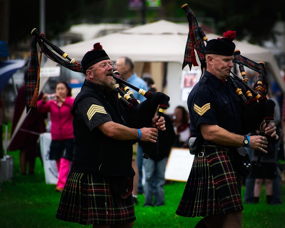 Two Men Playing Wind Instruments on Ground, bagpipes, band, blurred background