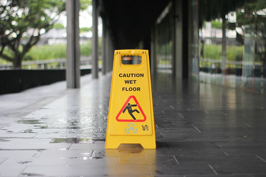 yellow Caution wet floor signage on wet pavement, communication