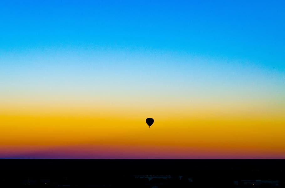 silhouette of hot air balloon under blue sky, sunrise, flying
