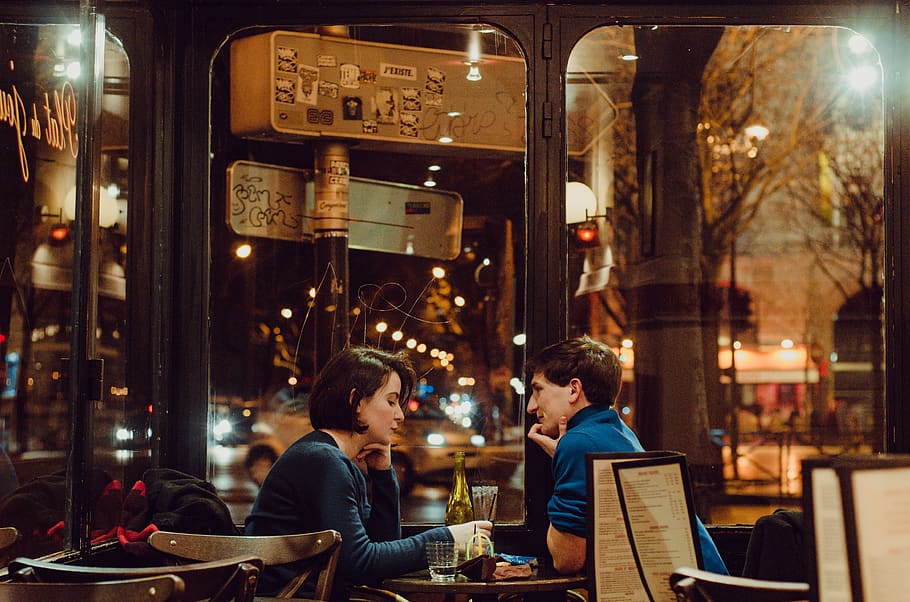 Selective Focus Photography of Man and Woman Sitting on Chair Inside Restaurant during Nighttime HD wallpaper