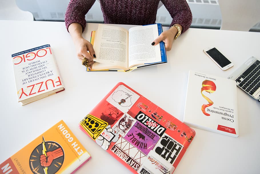 Person Holding Open Book on Table Inside Room, books, close-up HD wallpaper