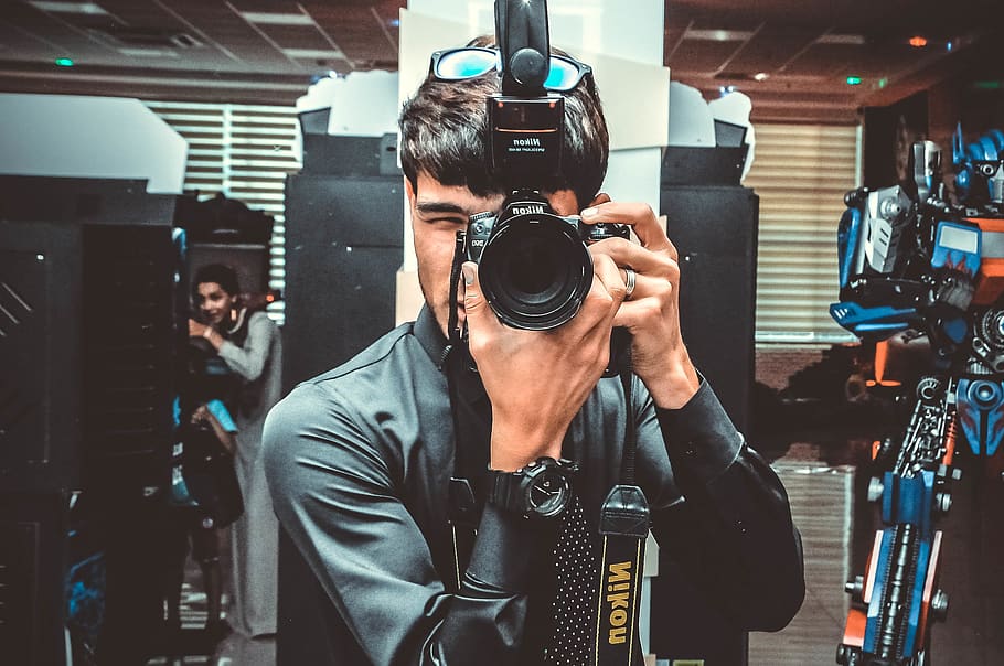 Photo of Man Using His Nikon Camera, blur, camera equipment, camera lens
