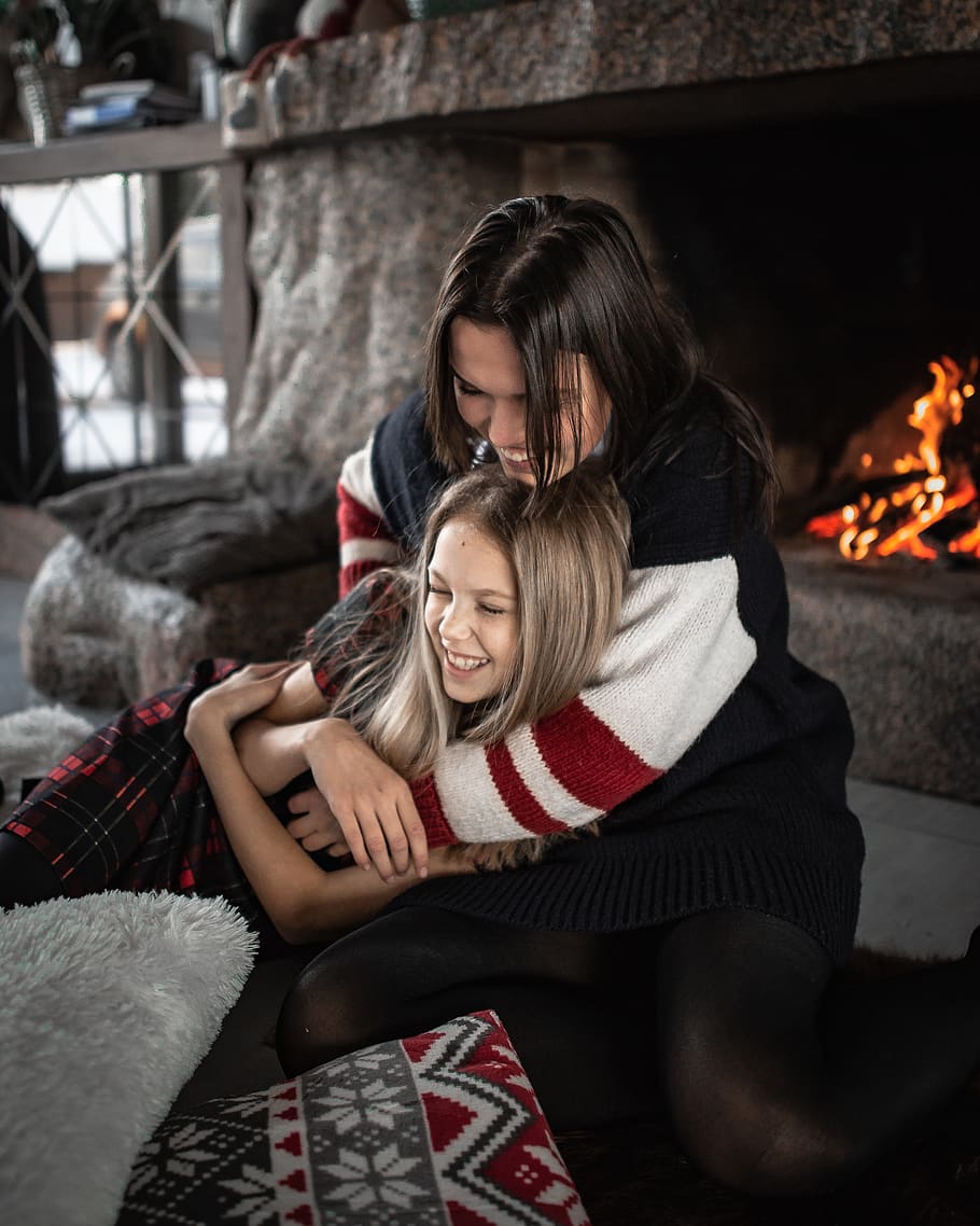 woman hugging girl while sitting near fireplace, women, togetherness