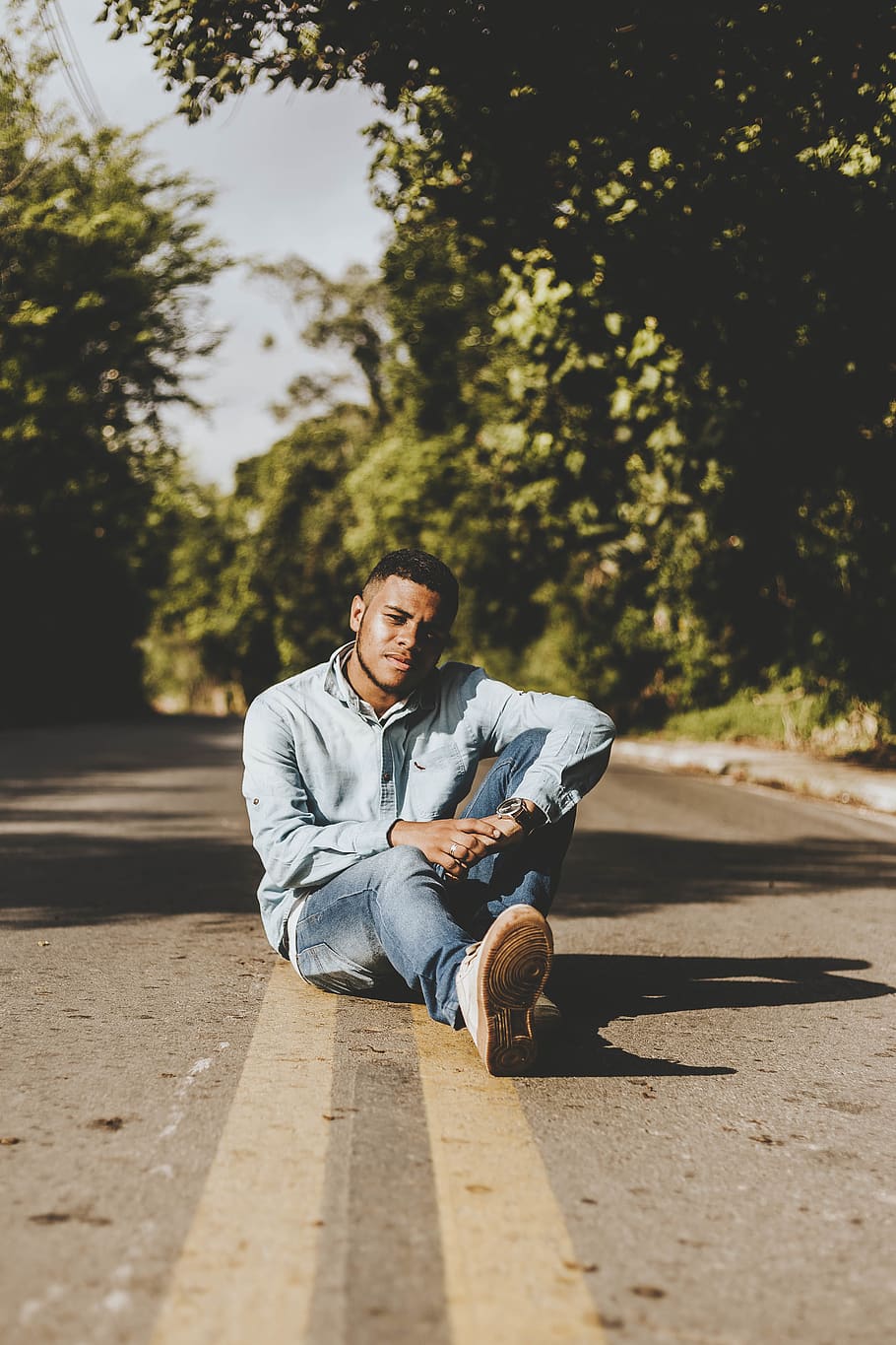 man sitting on road between tree duing daytime, one person, full length HD wallpaper