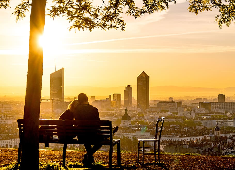 A couple sitting on a park bench while looking down at a city in France., HD wallpaper