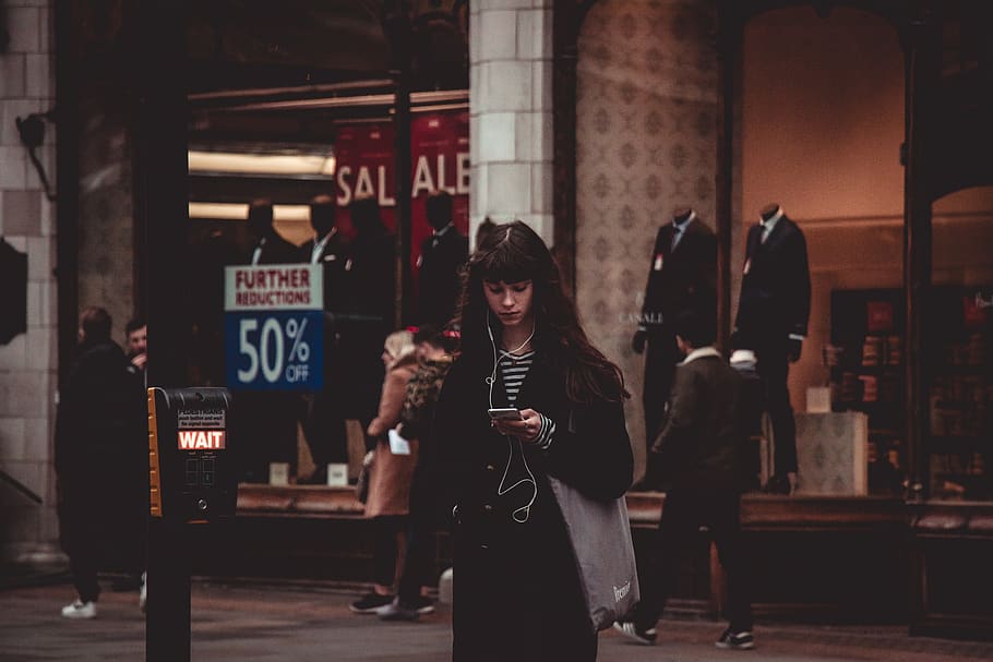 standing woman wearing black coat using smartphone and earphones, HD wallpaper