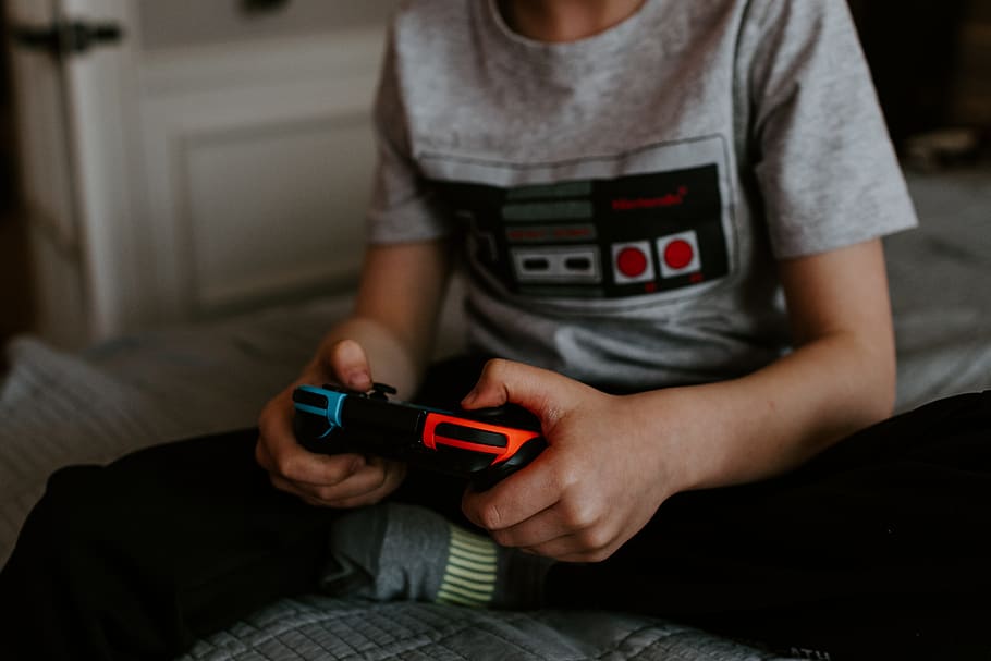 kid sitting on gray bed while playing, holding, technology, midsection HD wallpaper
