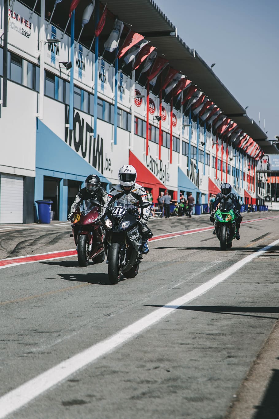 three race motorcycles with riders in the track, suit, helmet