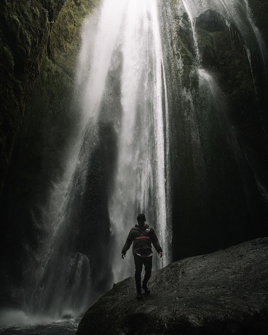 person standing on rock near waterfalls, hat, jacket, stone, wet HD wallpaper