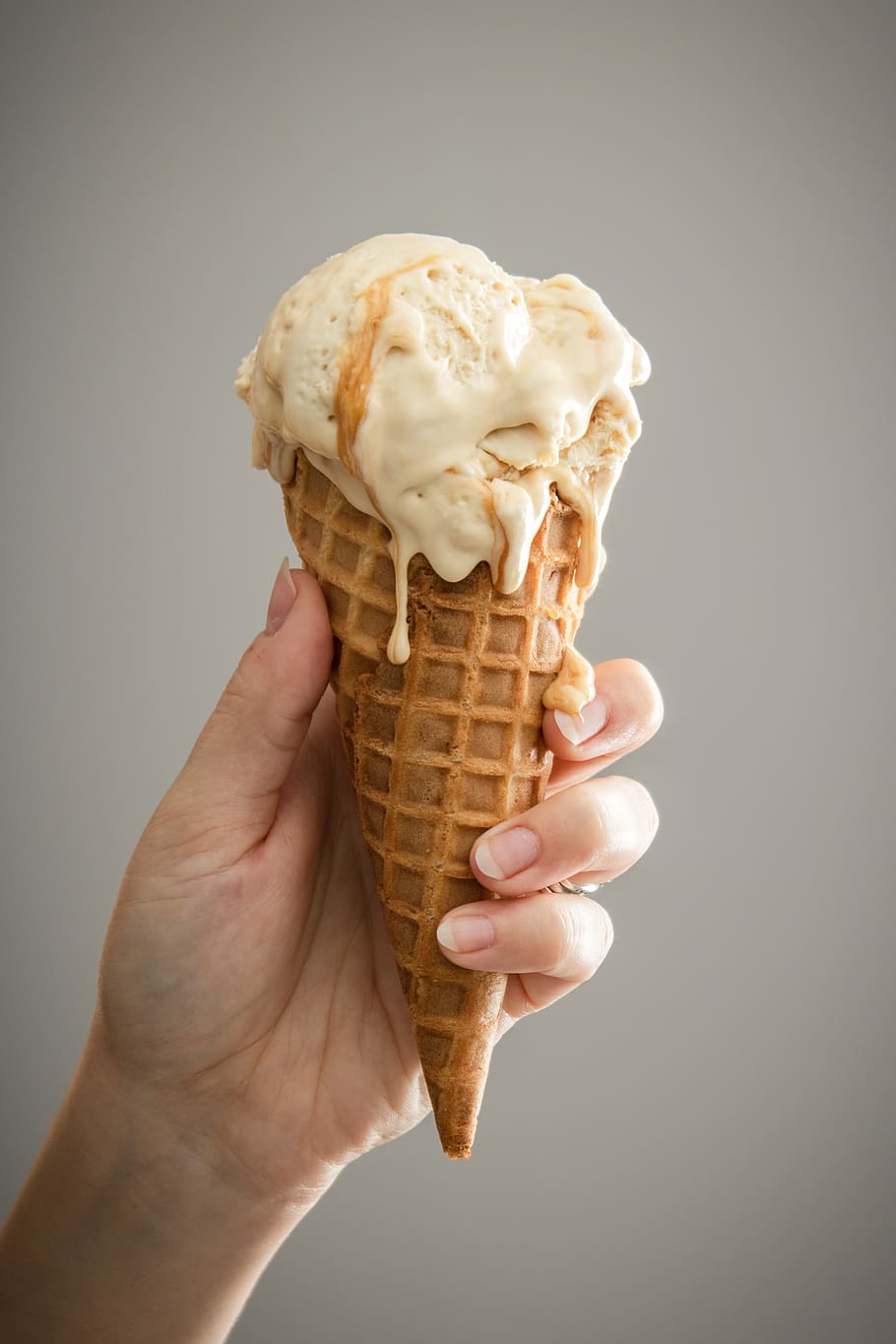 white ice cream on brown cone, food and drink, human hand, ice cream cone