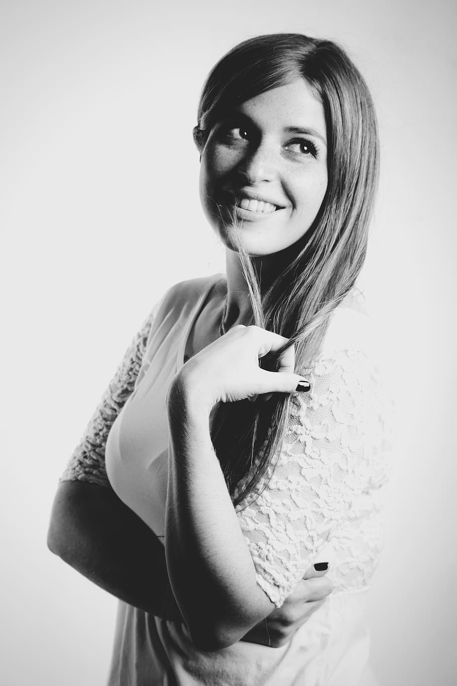 Grayscale Photo of Woman Wearing White Shirt While Holding Her Hair