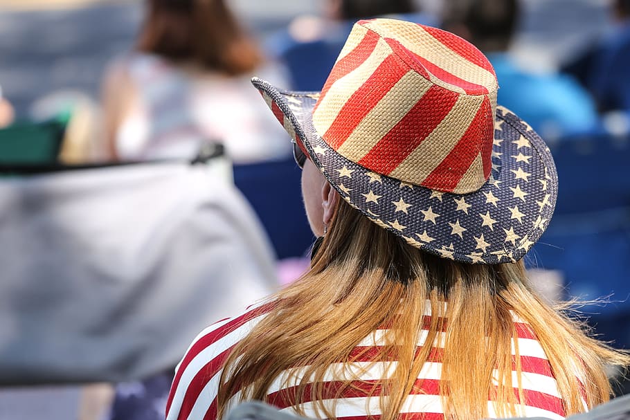 Rear view or seated woman wearing an American Flag hat at a parade.
