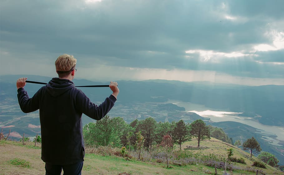 Man Wearing Hoodie Standing on Mountain Under Cloudy Sky, clouds HD wallpaper