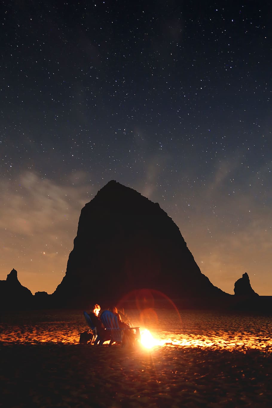 photo of couple sitting in front of bonfire near mountain, haystack rock HD wallpaper