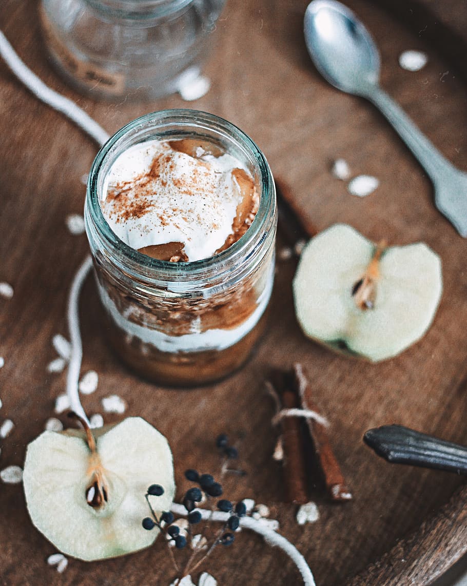 chocolate in clear glass jar near apple slices, cutlery, spoon