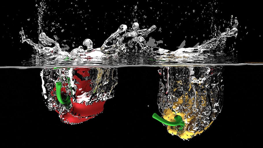 Two peppers splash into the clear water, Red, Yellow, bell pepper