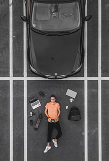 man lying on parking lot near black car, tech, flat, flatlay HD wallpaper