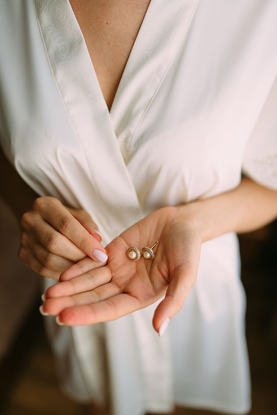 Pair of Gold-colored-and-white Pearl Stud Earrings in Woman's Palm