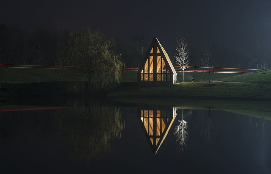 brown wooden house near bare tree with reflection on water at night time HD wallpaper