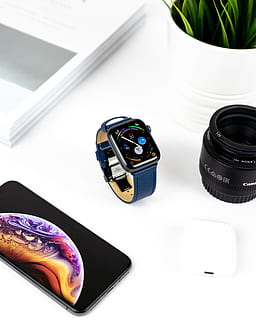 space grey aluminum case Apple Watch with blue leather band on table in between iPhone X and Canon zoom lens HD wallpaper