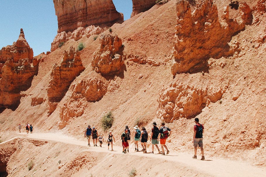 people walking on sand field, group of people, rock formation HD wallpaper