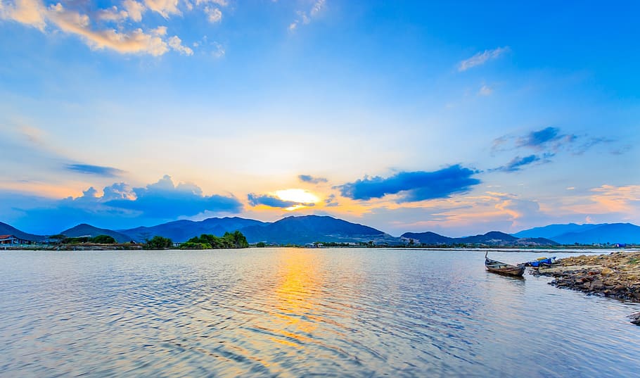 Canoe on Body of Water Near Mountain Range Under Golden Hour HD wallpaper