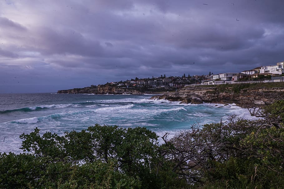 Body of Water Near Houses, beach, cliff coast, clouds, daylight HD wallpaper