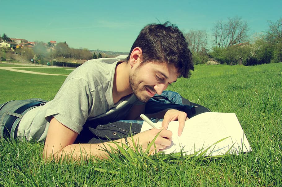 Man Writing on Book, boy, field, grass, green, happiness, hayfield, HD wallpaper