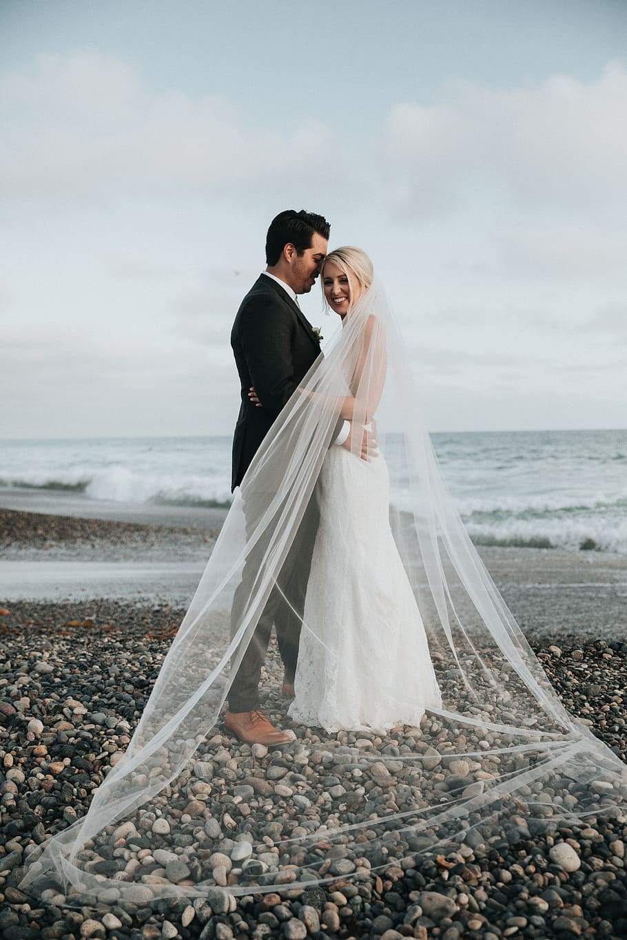 newly wedded couple standing on shore during daytime, person