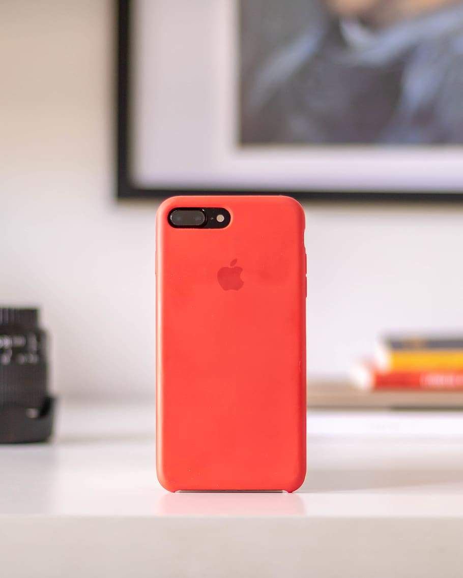 post-2016 iPhone with red case, focus on foreground, indoors HD wallpaper