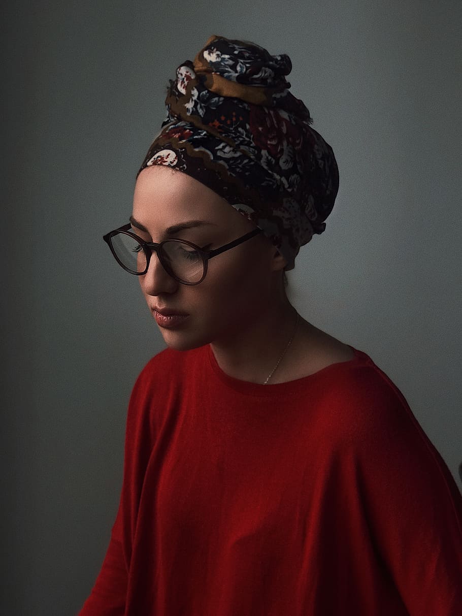 woman wearing floral turban, eyeglasses, and red boat-neck top
