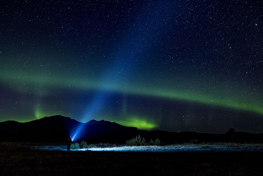 person holding lighted flashlight in dark sky, landscape, northern light HD wallpaper