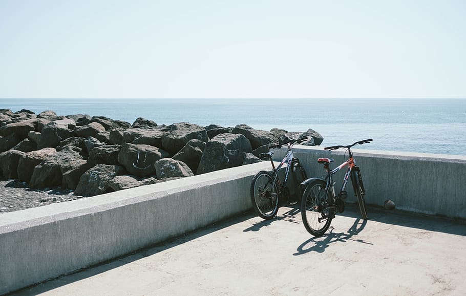 Two Bicycles Behind Gray Concrete Wall, barrier, beach, bike, HD wallpaper