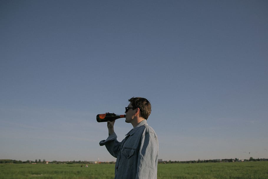 man drinking in bottle under gray sky, one person, field, environment HD wallpaper