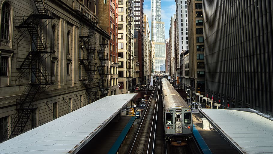train surrounded by buildings during daytime, vehicle, transportation