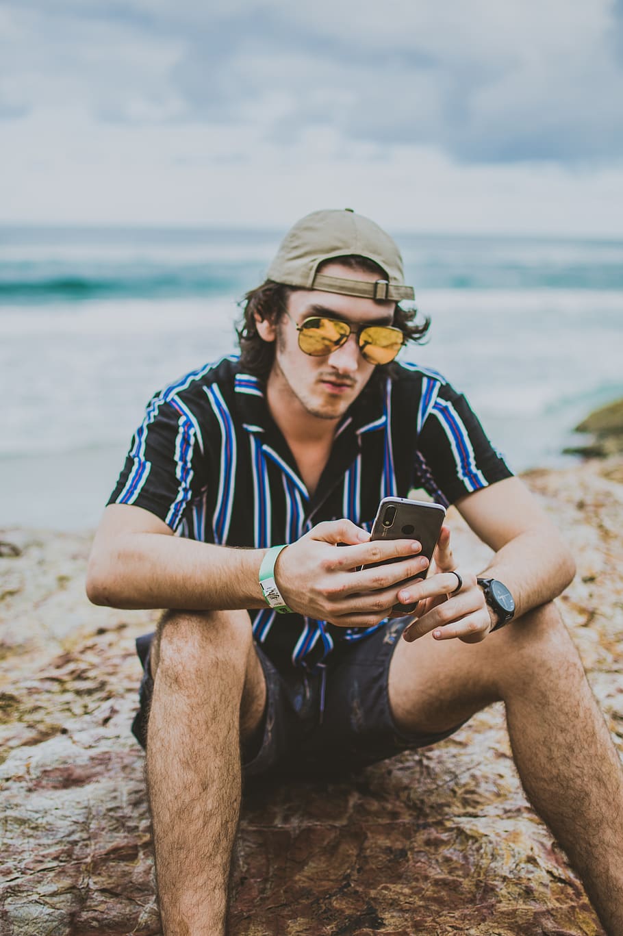 man holding smartphone while sitting on sand, human, person, beach HD wallpaper