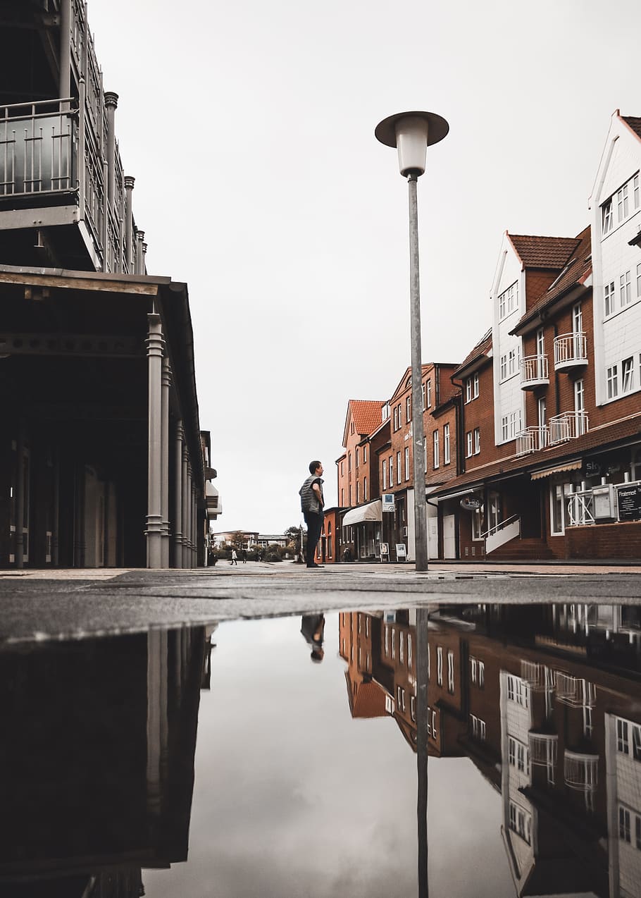 low-angle photography of man standing light post, puddle, person HD wallpaper