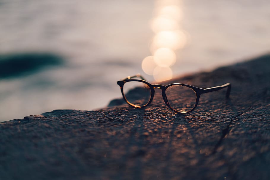 close-up photography of black framed clear lens sunglasses near body of water HD wallpaper